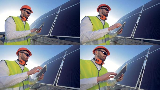 一位专家正在用他的平板电脑调节太阳能电池阵列的工作。绿色能源概念。