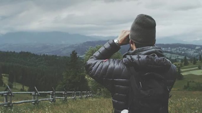 用双筒望远镜看的人。多山的地形