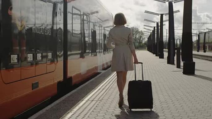 自信的女人带着行李走在火车站上