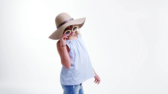 戴着帽子和太阳镜的女孩在白色背景下摆姿势