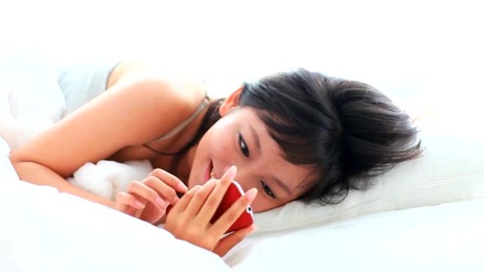 漂亮的年轻女子在床上使用手机
