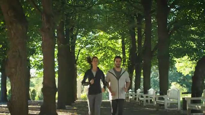 在公园晨跑期间，年轻的男人和女人朝着镜头前进。