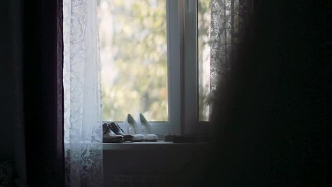 结婚戒指，新娘和新郎的鞋子仍然站在窗户上。仪式前的早上。右侧滑块