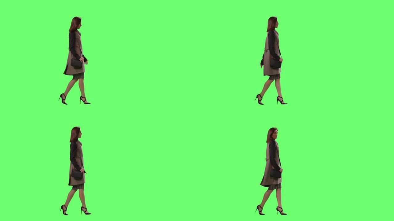 休闲的黑发女性正走在背景的模拟绿色屏幕上。