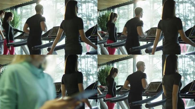 年轻的运动男女在运动健身房的跑步机上锻炼和跑步。