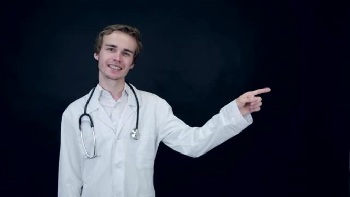 积极的医生看着相机，指着物品。竖起大拇指。包装照片