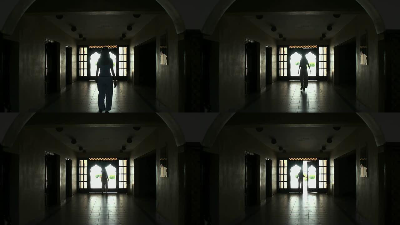 女人（剪影）穿过黑暗的阿拉伯大厅，走向阳光明媚的外部