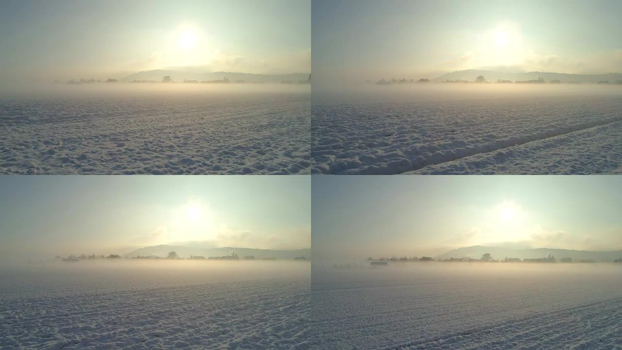 空中飞越被雪覆盖的雾蒙蒙的乡村，朝着郊区的小镇飞行