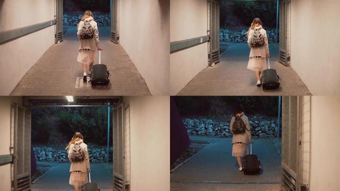 年轻女子背着手提箱穿过隧道。背着背包的女孩在城市里行走，旅行。慢动作