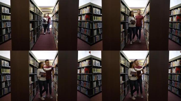 学生夫妇在图书馆的书架之间寻找书