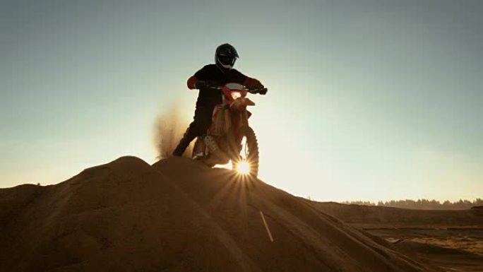 FMX摩托车专业越野车手站在沙丘上俯瞰越野赛道，然后向下行驶。