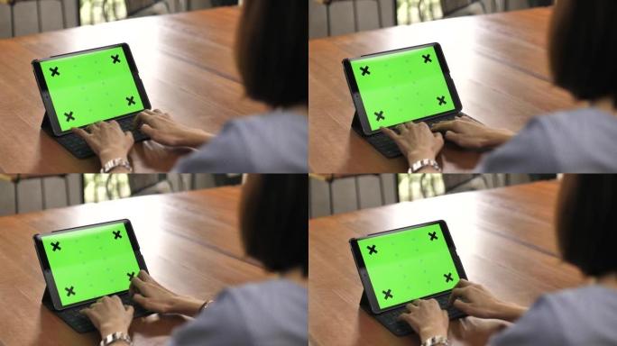 在数字平板电脑上绿屏上工作的女人的手的特写