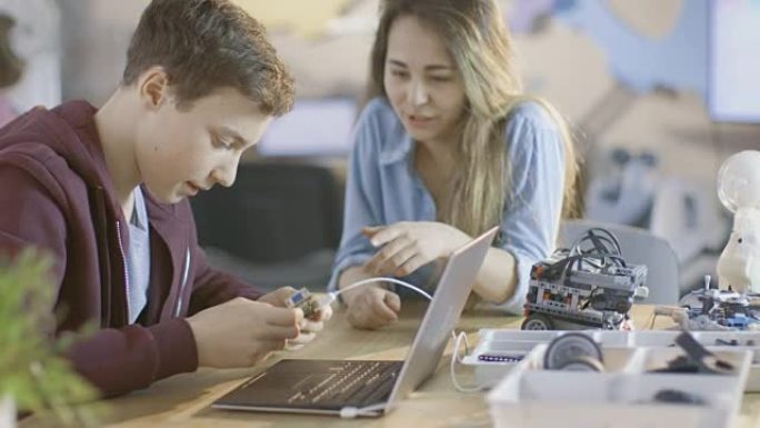 女孩和男孩在学校为他们的科学/机器人/工程课程提供带笔记本电脑的电子设备。