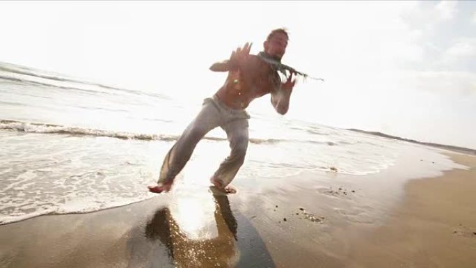 年轻的肌肉发达的人在海滩上做卡波耶拉后空翻