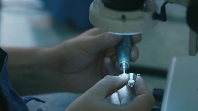 一家工厂的工程师正在用手电筒在显微镜下检查金属细节。