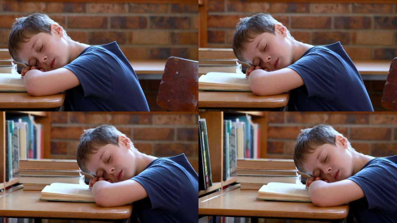 小男孩睡在教室里的书上