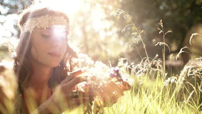 微笑的嬉皮士女孩躺在草丛中拿着野花