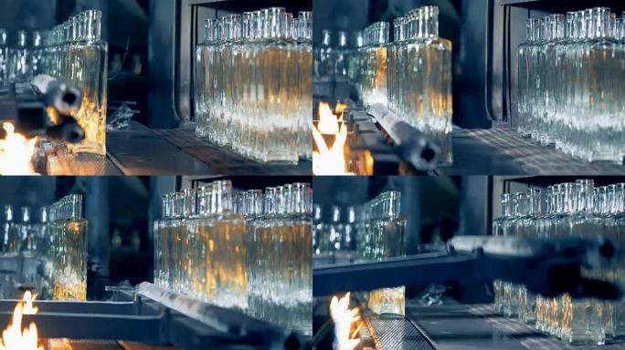 直排的水晶清洁玻璃瓶正在沿着传送带通过火移动并从其上重新安置
