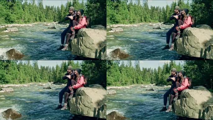夫妇在河上的一块岩石上休息