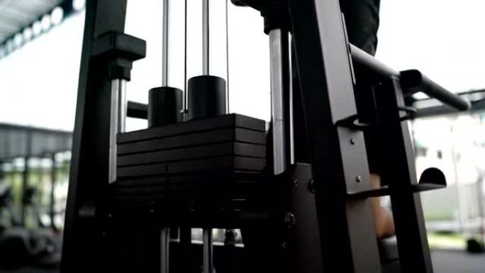 亚洲男子使用健身器在健身房锻炼