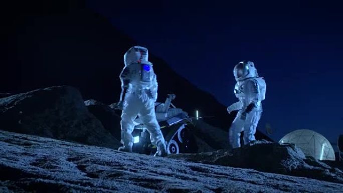 两名宇航员穿着宇航服在外星球上为表面探索任务准备太空车。关于太空殖民的未来概念。