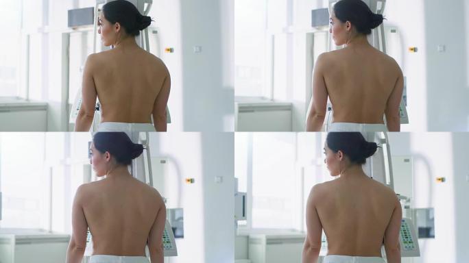 在医院里，裸露上身的女性病人正在接受乳房x光检查。健康年轻女性做癌症预防扫描。拥有高科技设备的现代化