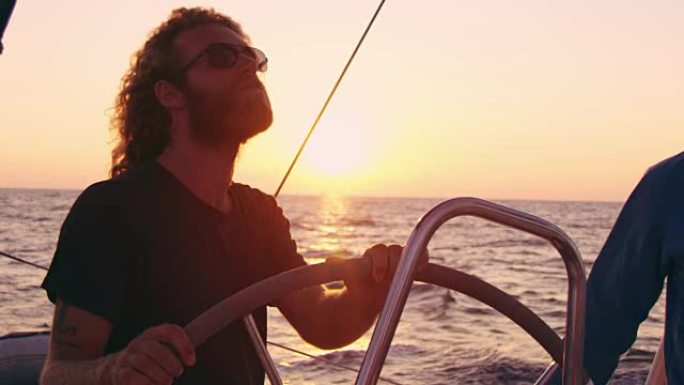 4k男子驾驶帆船在宁静、阳光明媚的日落海洋上，慢动作