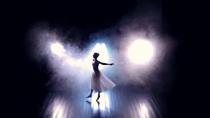 芭蕾舞演员在黑暗的舞台上跳高。