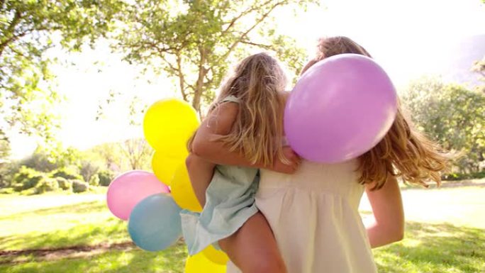 公园里带着五颜六色的气球快乐的母女俩