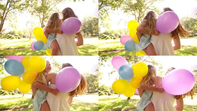 公园里带着五颜六色的气球快乐的母女俩