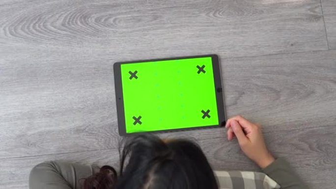女人在地板上使用绿色屏幕的白色平板电脑