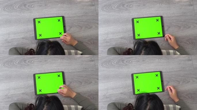 女人在地板上使用绿色屏幕的白色平板电脑