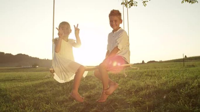 慢动作开朗的男孩和女孩坐在日落时摆姿势拍照