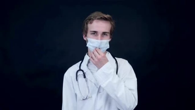 心烦意乱的医生取下医用口罩，看着屏幕。包装照片