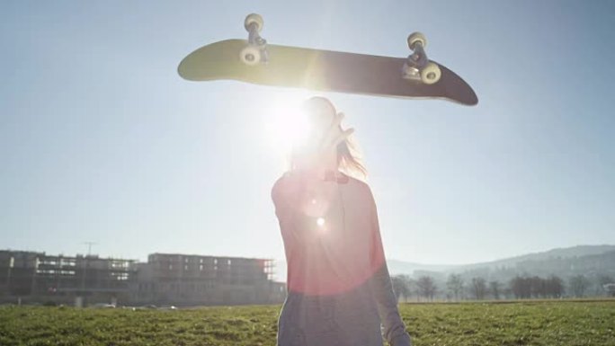 特写: 草地上的滑板手在空中对着太阳翻转滑板