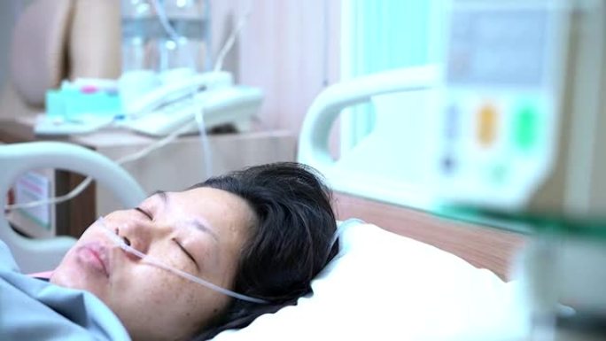 卧床不起的女性患者躺在病床上，从手术中恢复时接受输液。