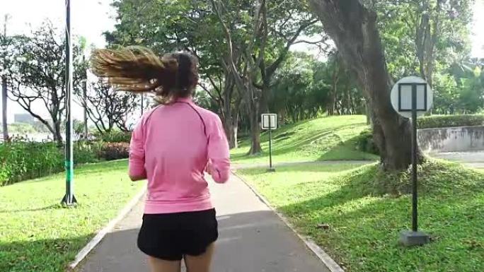 慢动作 -- 年轻的亚洲女人早上在人行道上跑步。年轻的体育亚洲女子在公园跑步。健身跑步运动人和健康生