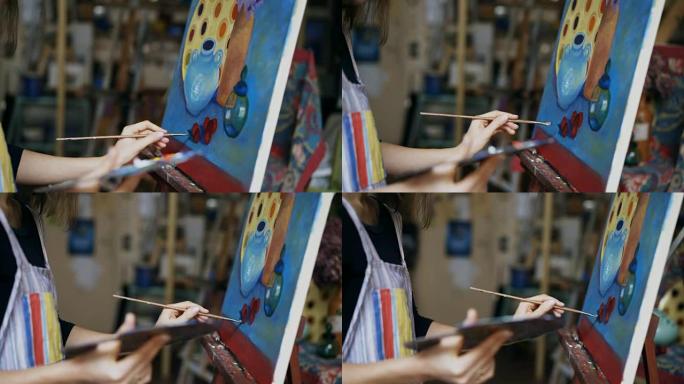 在艺术工作室的画布上画笔画静物画的女艺术家的特写跟踪镜头