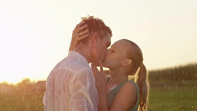 镜头耀斑: 金发女人在雨中亲吻时爱抚男友的脸。