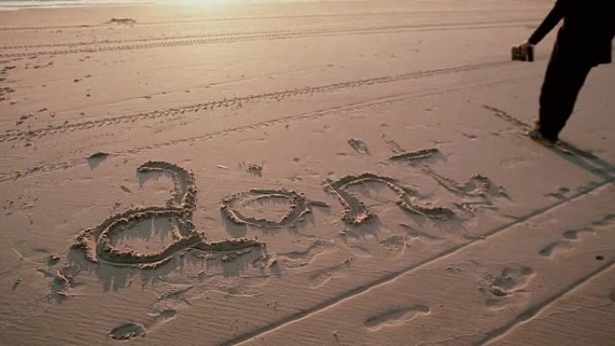 一个穿着黑色外套和牛仔裤的黑发男人在沙滩上写 “不要b”