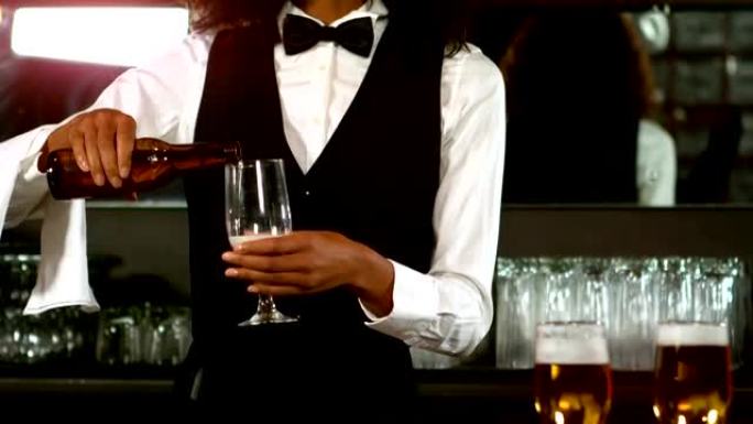 漂亮的酒吧服务员在玻璃杯里倒啤酒