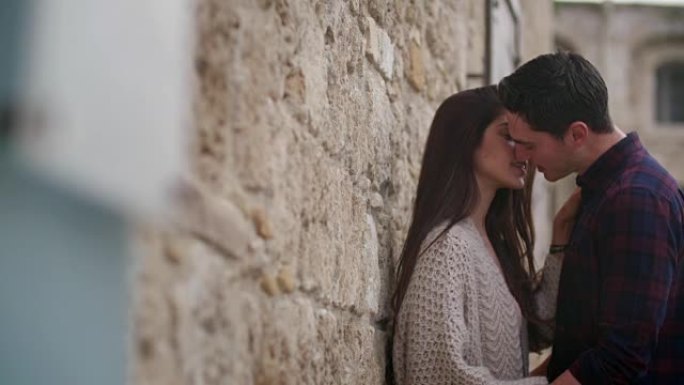 年轻夫妇在石墙前接吻