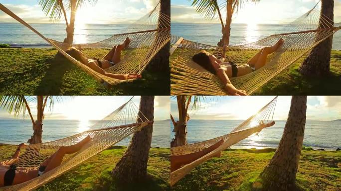 美丽的年轻女子日落时在热带吊床上放松。