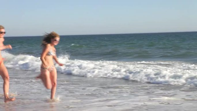 一群十几岁的朋友一起沿着海滩奔跑