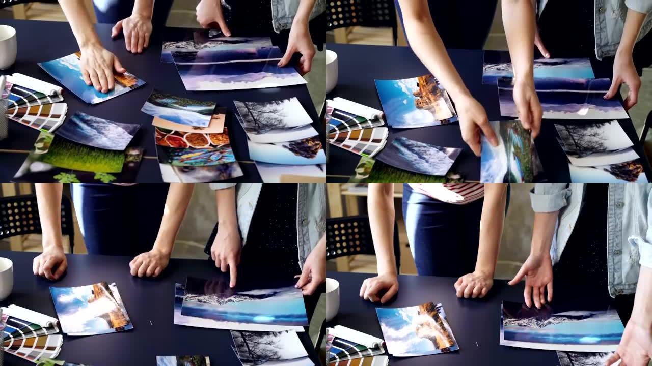 在现代办公室中，女性的双手将照片放在桌子上的俯仰镜头。女性设计师正在按颜色和图像对图片进行分组，并讨