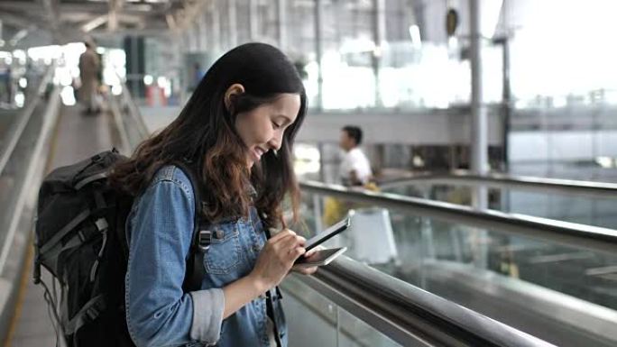 在机场航站楼的自动扶梯上使用智能手机的女人