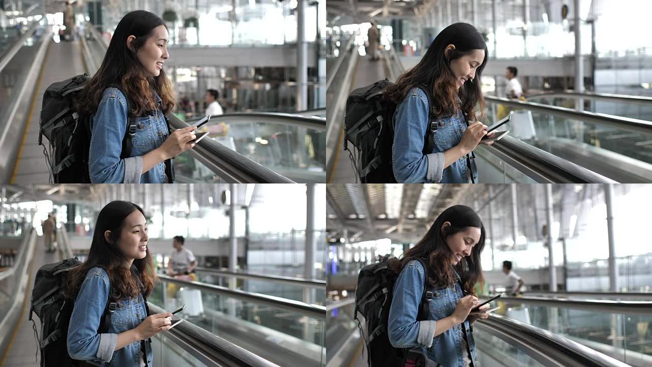 在机场航站楼的自动扶梯上使用智能手机的女人