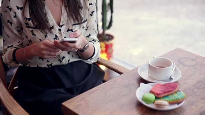 年轻漂亮的女人坐在时尚的咖啡馆里用手机