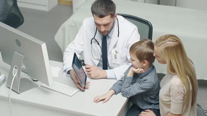 男医生在平板电脑的帮助下咨询小男孩和他的母亲。他们微笑着热情地交谈。