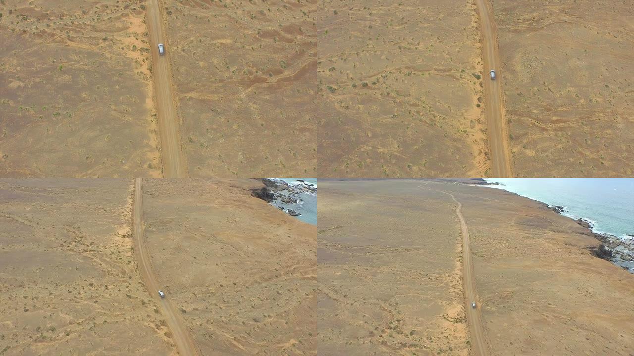 空中: 汽车驶过海洋旁的巨大沙质沙漠